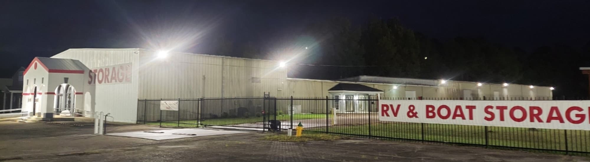 Creekside Self Storage lit up at night behind its fenced and gated entrance
