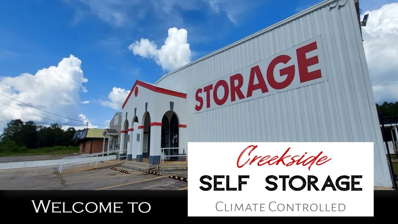 Creekside Self Storage building with its red STORAGE sign and arched front entrance under a blue sky